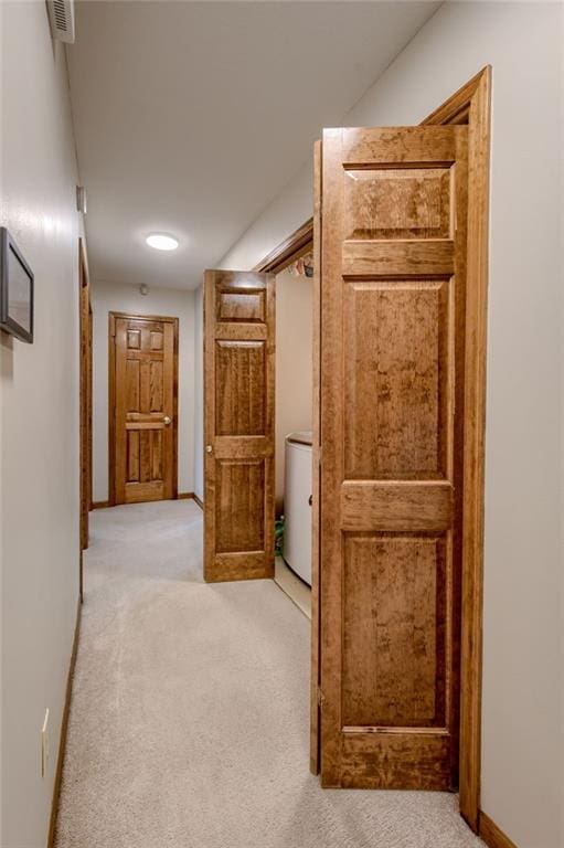 hall with light colored carpet, baseboards, and visible vents
