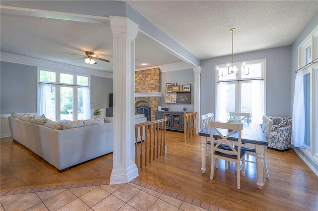 living room with ornate columns, a ceiling fan, tile patterned floors, ornamental molding, and a textured ceiling