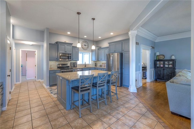 kitchen featuring stainless steel appliances, a kitchen island, a breakfast bar area, gray cabinets, and recessed lighting
