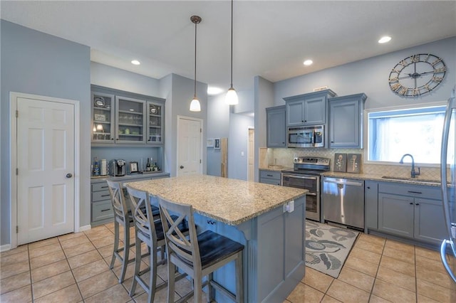 kitchen featuring stainless steel appliances, a kitchen breakfast bar, a center island, tasteful backsplash, and light tile patterned flooring