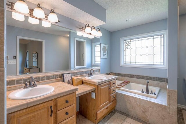 bathroom featuring tile patterned floors, a garden tub, vanity, decorative backsplash, and a textured ceiling