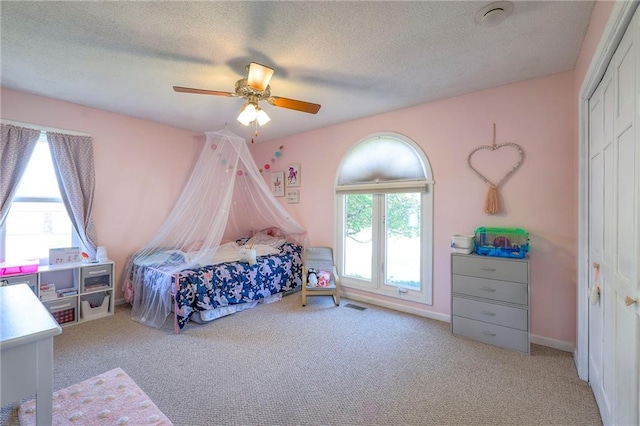 carpeted bedroom with a textured ceiling, a closet, and ceiling fan