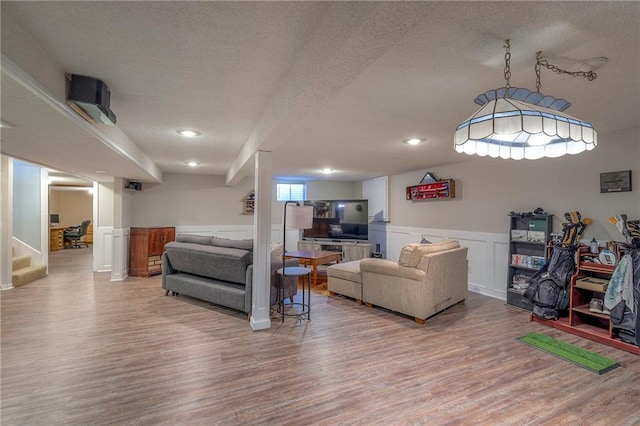living area with a textured ceiling, wood finished floors, a wainscoted wall, stairway, and recessed lighting