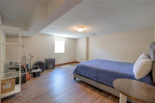 bedroom featuring wood finished floors, baseboards, and a textured ceiling