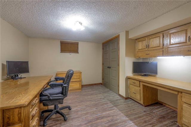 home office with a textured ceiling, wood finished floors, and baseboards