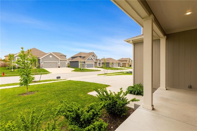 view of yard with driveway, a residential view, and a garage