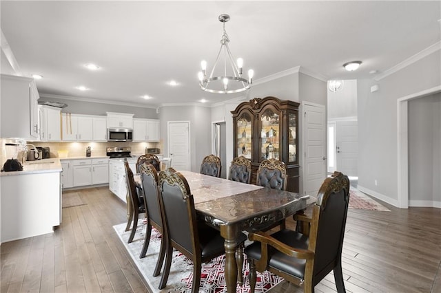 dining space featuring ornamental molding, baseboards, recessed lighting, a chandelier, and light wood-style flooring