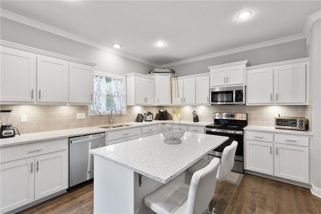kitchen featuring a kitchen island, crown molding, appliances with stainless steel finishes, a sink, and white cabinets