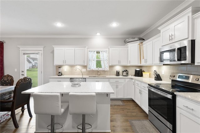 kitchen with backsplash, a sink, stainless steel appliances, white cabinetry, and dark wood-type flooring