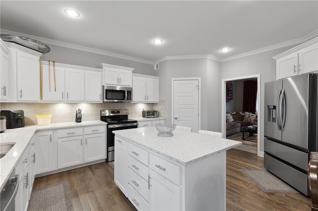 kitchen featuring a center island, ornamental molding, white cabinetry, and appliances with stainless steel finishes