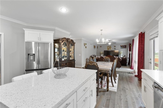kitchen featuring crown molding, open floor plan, a chandelier, light wood finished floors, and stainless steel appliances