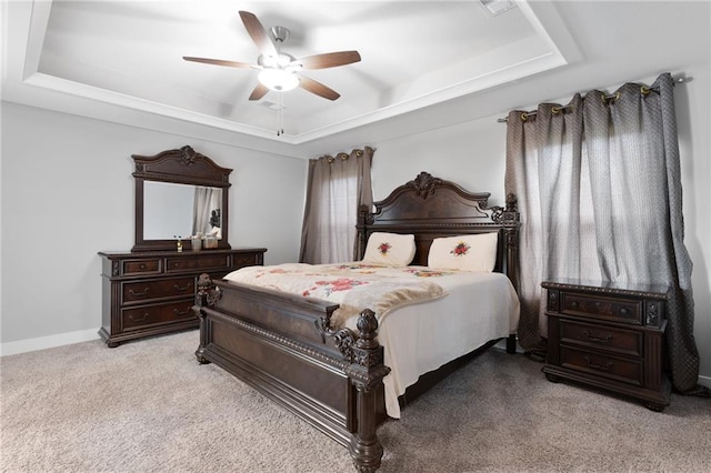 carpeted bedroom featuring a raised ceiling, baseboards, and a ceiling fan