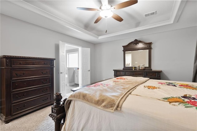 bedroom featuring a raised ceiling, ceiling fan, visible vents, and connected bathroom