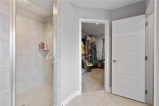 full bathroom with a spacious closet, tile patterned flooring, and a stall shower