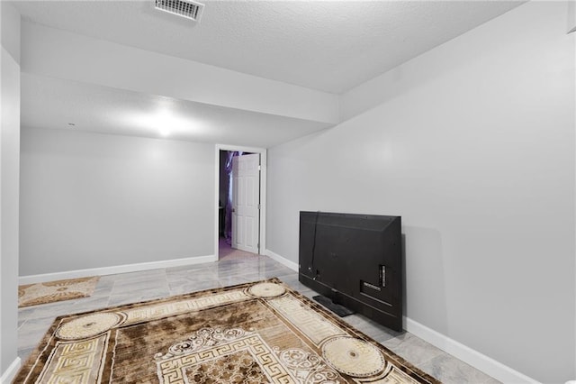 unfurnished room with a textured ceiling, baseboards, and visible vents