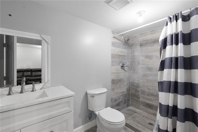 full bathroom featuring a textured ceiling, visible vents, a tile shower, vanity, and toilet