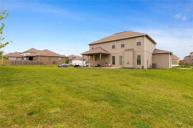 back of house featuring central air condition unit, a lawn, and fence