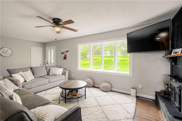 1204 E 223rd St, Cleveland, MO 64734 - living area featuring ceiling fan, a textured ceiling, a fireplace, wood finished floors, and baseboards