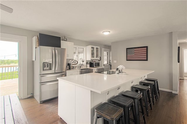 1204 E 223rd St, Cleveland, MO 64734 - kitchen featuring a breakfast bar area, white cabinetry, appliances with stainless steel finishes, and wood finished floors