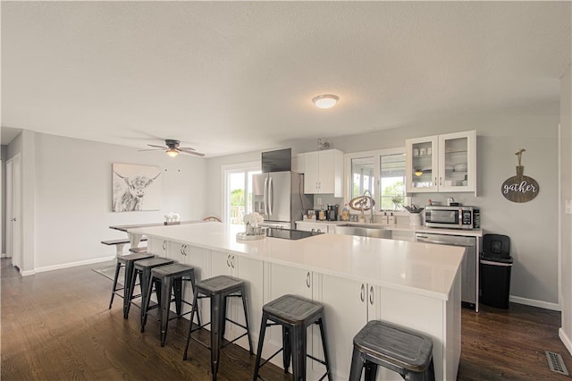 1204 E 223rd St, Cleveland, MO 64734 - kitchen with a breakfast bar area, dark wood-style flooring, appliances with stainless steel finishes, a sink, and white cabinetry