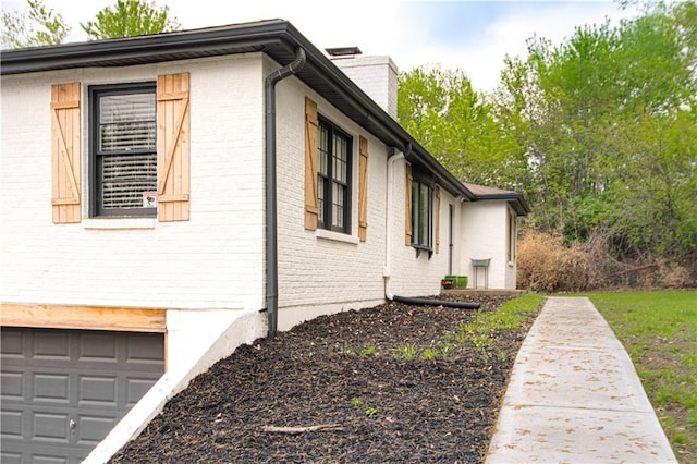 1204 E 223rd St, Cleveland, MO 64734 - view of side of property with a garage, a chimney, and brick siding