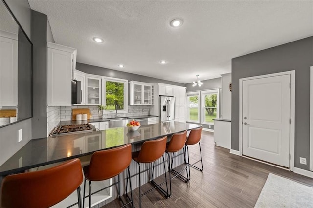 14305 S Gammon Rd, Greenwood, MO 64034 - kitchen with appliances with stainless steel finishes, a peninsula, decorative backsplash, glass insert cabinets, and white cabinets