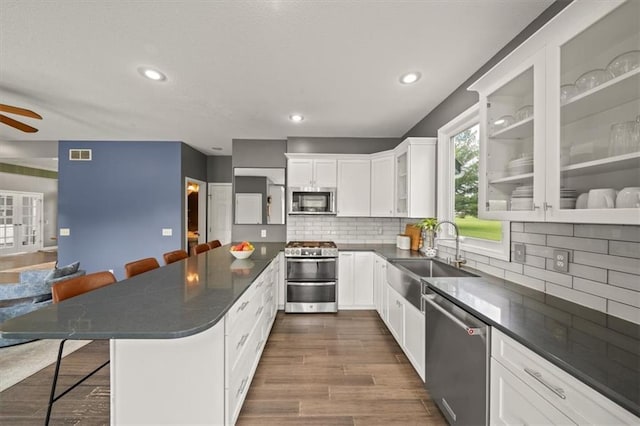 14305 S Gammon Rd, Greenwood, MO 64034 - kitchen featuring appliances with stainless steel finishes, a kitchen breakfast bar, white cabinets, glass insert cabinets, and a ceiling fan