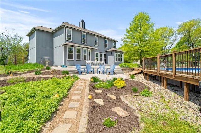 14305 S Gammon Rd, Greenwood, MO 64034 - back of property with a patio, a chimney, and a wooden deck