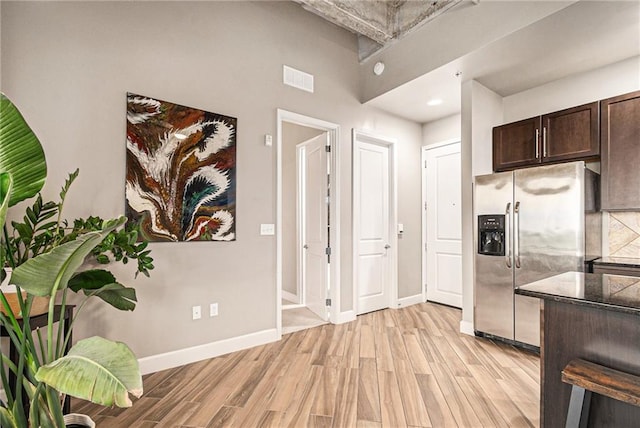 2940 Baltimore Ave Unit 1407, Kansas City, MO 64108 - kitchen with stainless steel fridge, light wood finished floors, dark brown cabinetry, decorative backsplash, and dark stone countertops