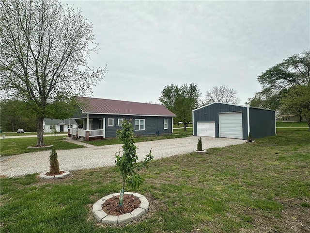 view of front facade with a garage, a front yard, an outdoor structure, driveway, and metal roof