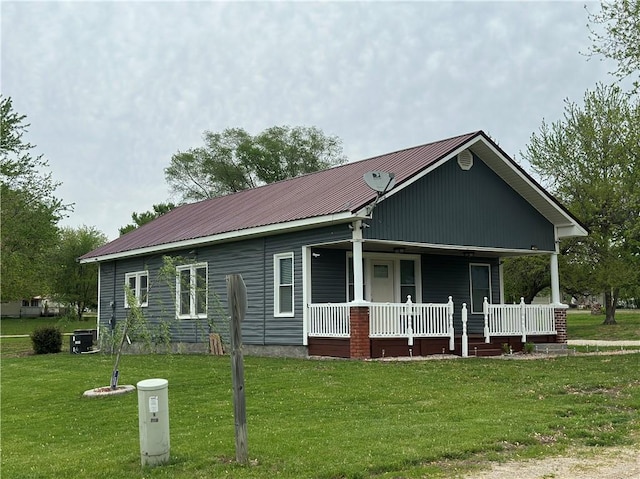 view of front of home featuring a front lawn, covered porch, and metal roof