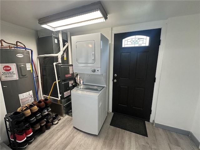 washroom featuring laundry area, stacked washer / dryer, light wood-type flooring, heating unit, and electric water heater