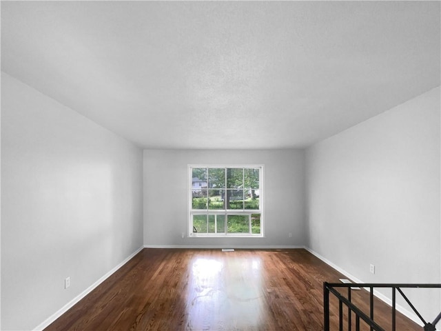 spare room with baseboards and wood finished floors