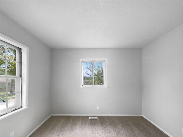 carpeted spare room featuring visible vents and baseboards