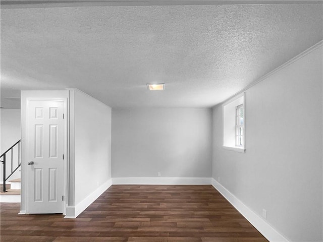 below grade area featuring baseboards, a textured ceiling, wood finished floors, and stairway