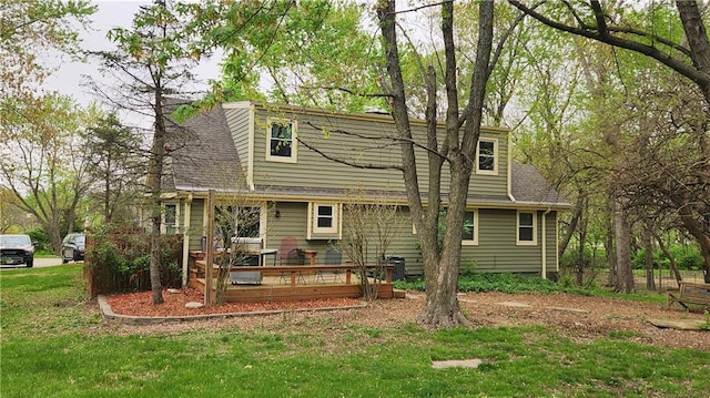 back of house with a yard, a deck, and roof with shingles