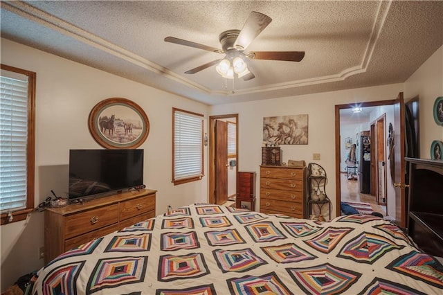 bedroom with a ceiling fan, a textured ceiling, and a tray ceiling