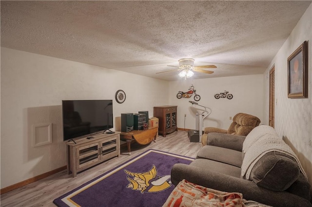 living area featuring baseboards, a ceiling fan, a textured ceiling, and wood finished floors