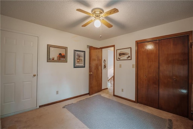 unfurnished bedroom featuring baseboards, carpet flooring, a textured ceiling, and a closet