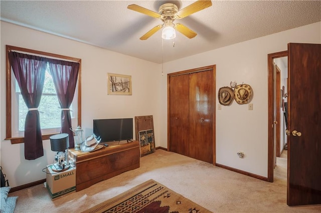 carpeted office featuring baseboards, a ceiling fan, and a textured ceiling