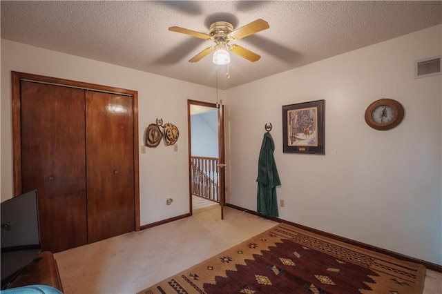 bedroom with a textured ceiling, light colored carpet, visible vents, baseboards, and a closet