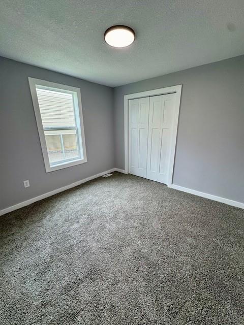 403 W Cedar St, Waverly, MO 64096 - unfurnished bedroom with a textured ceiling, a closet, carpet, and baseboards
