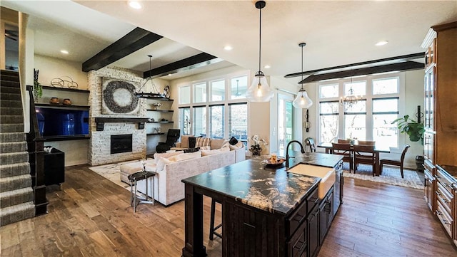 kitchen featuring a sink, dark wood-style flooring, a stone fireplace, and a wealth of natural light