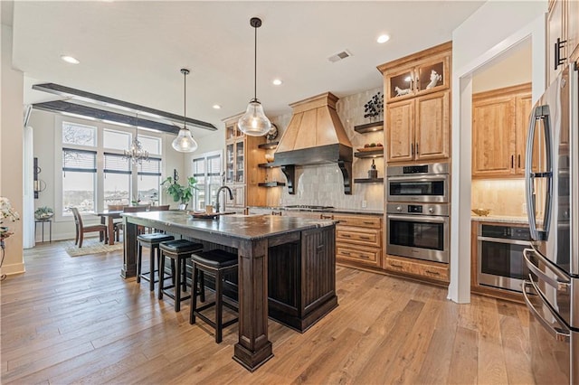 kitchen with backsplash, a kitchen bar, visible vents, custom range hood, and stainless steel appliances