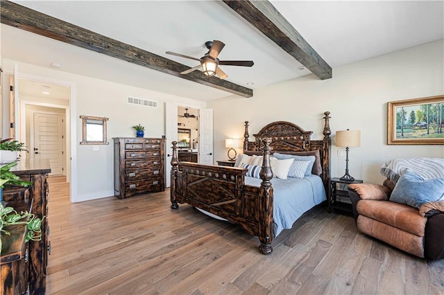 bedroom featuring visible vents, light wood finished floors, baseboards, and beamed ceiling