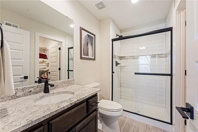 full bath with visible vents, vanity, toilet, and a shower stall