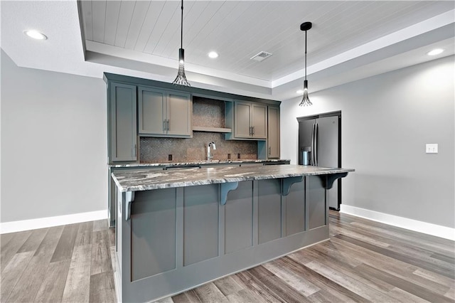 kitchen featuring a kitchen island, baseboards, light wood finished floors, and a raised ceiling