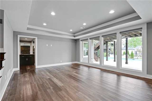 unfurnished living room featuring visible vents, baseboards, dark wood-type flooring, recessed lighting, and a raised ceiling