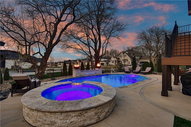 pool at dusk with a patio, an in ground hot tub, fence, and a fenced in pool