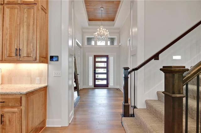 11212 W 170th Pl, Overland Park, KS 66221 - foyer entrance with stairway, light wood-style flooring, a chandelier, a raised ceiling, and baseboards